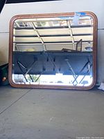 Front view of rectangular mirror with beveled glass and wood frame showing reflective surface and surroundings.
