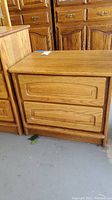 Front view of the oak nightstand showing two drawers with recessed panel detailing and a natural wood finish.