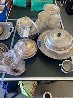Overview of assorted metal serving trays and covered platters on a table showing various shapes and sizes.