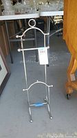 Front view of the metal free standing toilet paper holder, showing the horizontal bar and overall structure.