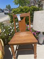 Front view of vintage solid wood chair showing slatted seat and carved backrest