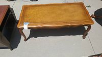 Full top and leg view of Vintage French Provincial leather inlaid coffee table showing scalloped edges, leather top and curved legs.