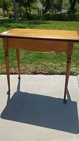 Full view of the vintage wooden game table showing front legs and smooth wood surface.