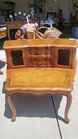 Full view of vintage French provincial style 2-tier side table showing wooden frame, cabriole legs, two drawers in the center, and mesh panel doors on sides with leather inlaid top.