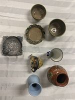 Eight assorted ceramic items including various vases, ashtray, soap dish set, and Tanuki figurine on a white fabric surface.