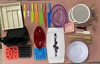 Overview of all items on green cloth, showing knives, bowls, trays, utensils, glasses, and storage items.