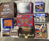 Overview of puzzles in original boxes showcasing variety of jigsaw themes and metal puzzles included in set.
