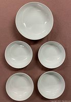 Top view of one large serving bowl and four smaller bowls arranged in a pattern, showing shape and size difference.