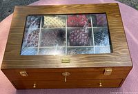 Woodgrain finish necktie storage box with glass lid locked and showing 8 ties in compartments.
