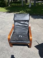 Front view of wooden framed chair with black seat cover placed outdoors.