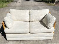 Front view of love seat couch with cream cushions showing staining