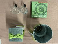 Overhead photo showing all four items: two hanging glass vases, My Crop Circle growing set box, bonsai tree kit box with ribbon, and silver planter pot.