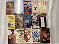 Photo shows all 15 VHS tapes laid out. Titles visible include Monty Python collections, Ripping Yarns, children's Disney tape, two yoga instructional tapes, and feature films including Gone with the Wind, The Big Chill, Gosford Park, and A Christmas Carol.