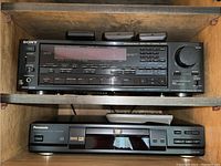 Two electronic components on wooden shelves: Sony stereo receiver above and Panasonic DVD player below