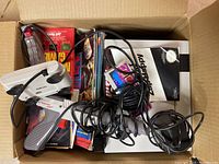 Box containing two Nintendo Zapper light gun controllers and assorted game magazines and manuals