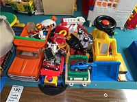 Overview photo showing the variety of toy vehicles including Tonka truck, fire truck, construction truck, blue sports car, and small accessories.