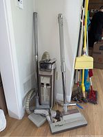 Full view of vintage Electrolux upright vacuum with attached hose, metal extension wand, and floor nozzle tipped to the side.