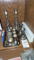 Overall lot view: tray with cordial cups, candlesticks, serving utensils and funnel