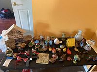 Full view of all bird collectibles on table including birdhouses, figurines, and plaque