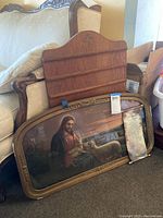 Framed Jesus with lambs wall art leaning against furniture, showing ornate gold frame with chip and part of 23rd Psalm board and wooden note board behind