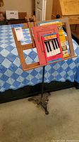 Wooden foldable music stand upright with several pieces of sheet music and songbooks displayed on it.
