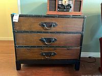 Front view of the wooden and faux leather 3-drawer chest showing the metal riveted edges and hardware handles.