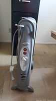 Full view of gray Bionaire portable space heater standing on the floor with power cord wrapped around handle.