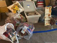 Wide view showing bags and bins containing assorted Thanksgiving decorative items including candle holders, pillow, and various small decor pieces.
