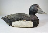 Side view of the carved wooden ring-necked duck decoy showing painted feather details and glass eye.