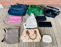 All ten vintage handbags grouped on wooden floor showing variety of styles and materials.