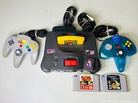 Overhead shot of console, two controllers, cables, adapter and three cartridges
