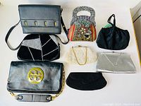 Photo shows all 8 purses arranged on a white surface including evening bags and larger purses for condition and style overview.