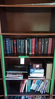 Showcase of three shelves with assorted hardcover books in worn condition