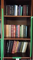 Bookshelves with worn hardcover and paperback books including reference and literature books