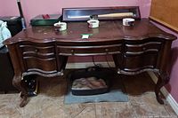 Front view of the carved wood desk showing scalloped edge, multiple drawers, and surface wear.