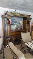 Front view of large wood entertainment system with decorative carved columns and artwork insert depicting horses.