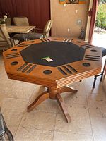 Side angle view showing octagonal shape, black felt center, cup holders, chip trays, and wooden finish on the poker table.