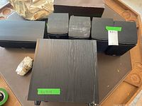 Six PSB speakers including a subwoofer, a center channel, and four bookshelf speakers arranged on table with visible labels and some wear.