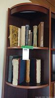 Shelf with eight vintage books including two with heavily damaged covers and worn spines, showing wear from age.