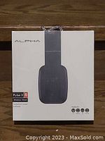 Front of the retail box showing ALPHA brand, Pulse X model, wireless/wired headphones, and packaging in black and white design.