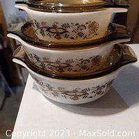 Stacked view of the three Pyrex casserole dishes showing the brown floral vine pattern and lids