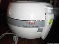 Side view of white T-fal ActiFry Original airfryer showing brand label and handle with release button.
