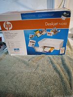 Photo of box top showing HP Deskjet F4280 all-in-one printer, scanner, copier with product image and features.