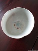 Top view of porcelain bowl showing interior glaze with multicolor brush strokes and light cream background.