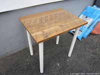 Side view of the pine wood table showing wood grain and white steel legs.