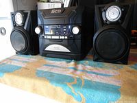 Front view of the Venturer stereo system setup with two speakers on sides, showing control panel, 5-CD carousel, and speaker components.