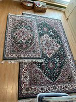 Large and smaller matching area rugs displayed on wooden floor, showing full pattern and fringed edges.