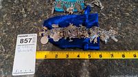 Two charm bracelets laid on a blue velvet pouch beside a measuring tape