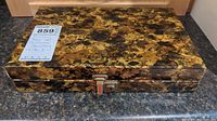 Closed decorative jewelry box with marbled gold and black finish and a latch