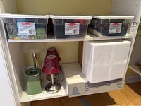 Shelving with various lamps and votive candle holders alongside storage bins